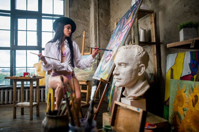 Woman in artist's studio painting on canvas. 