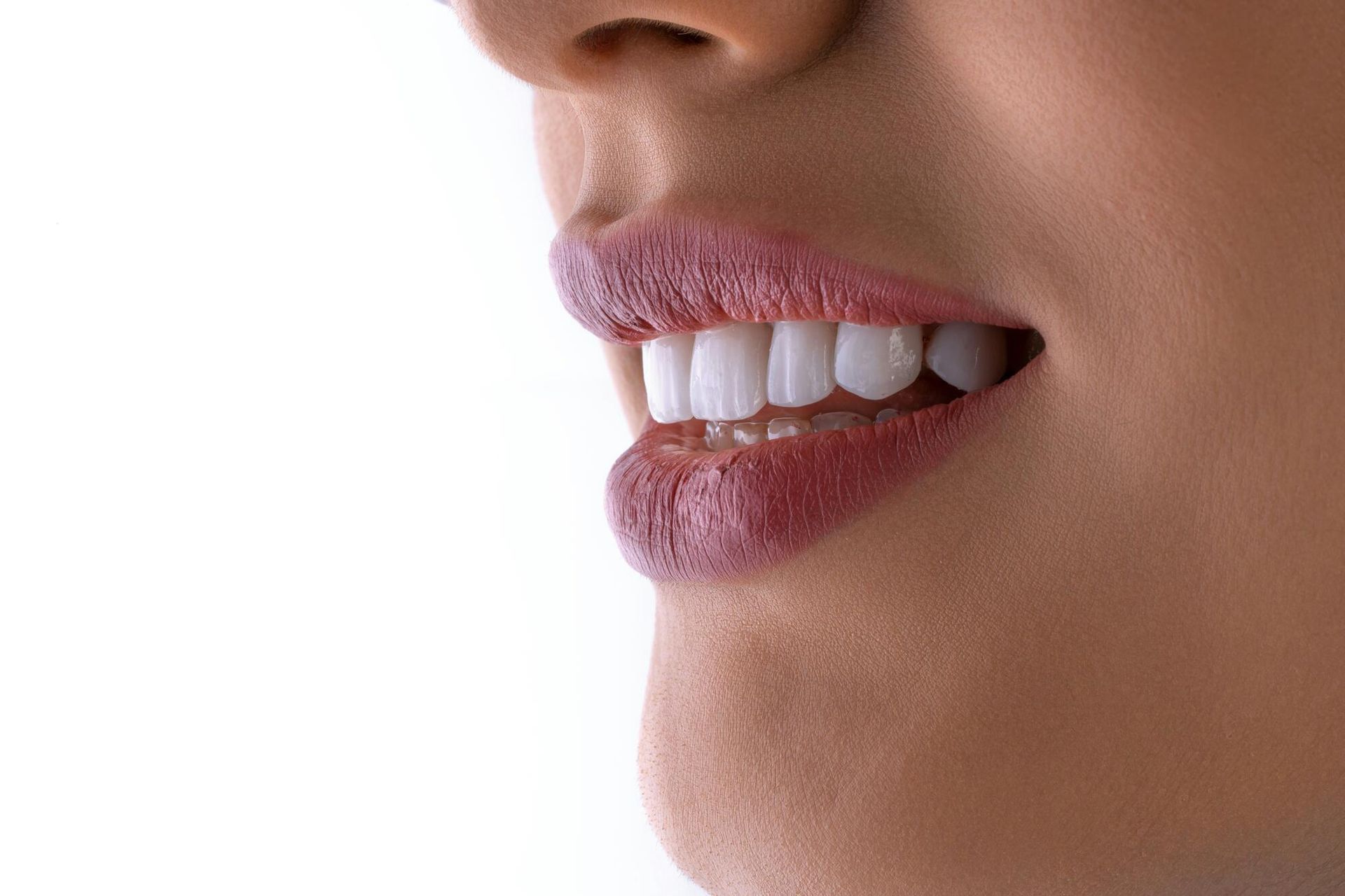 Close-up of a woman smiling, showing bright white teeth and full, red lips.