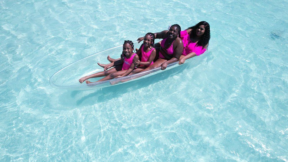 Four people in pink swimsuits in crystal clear water 