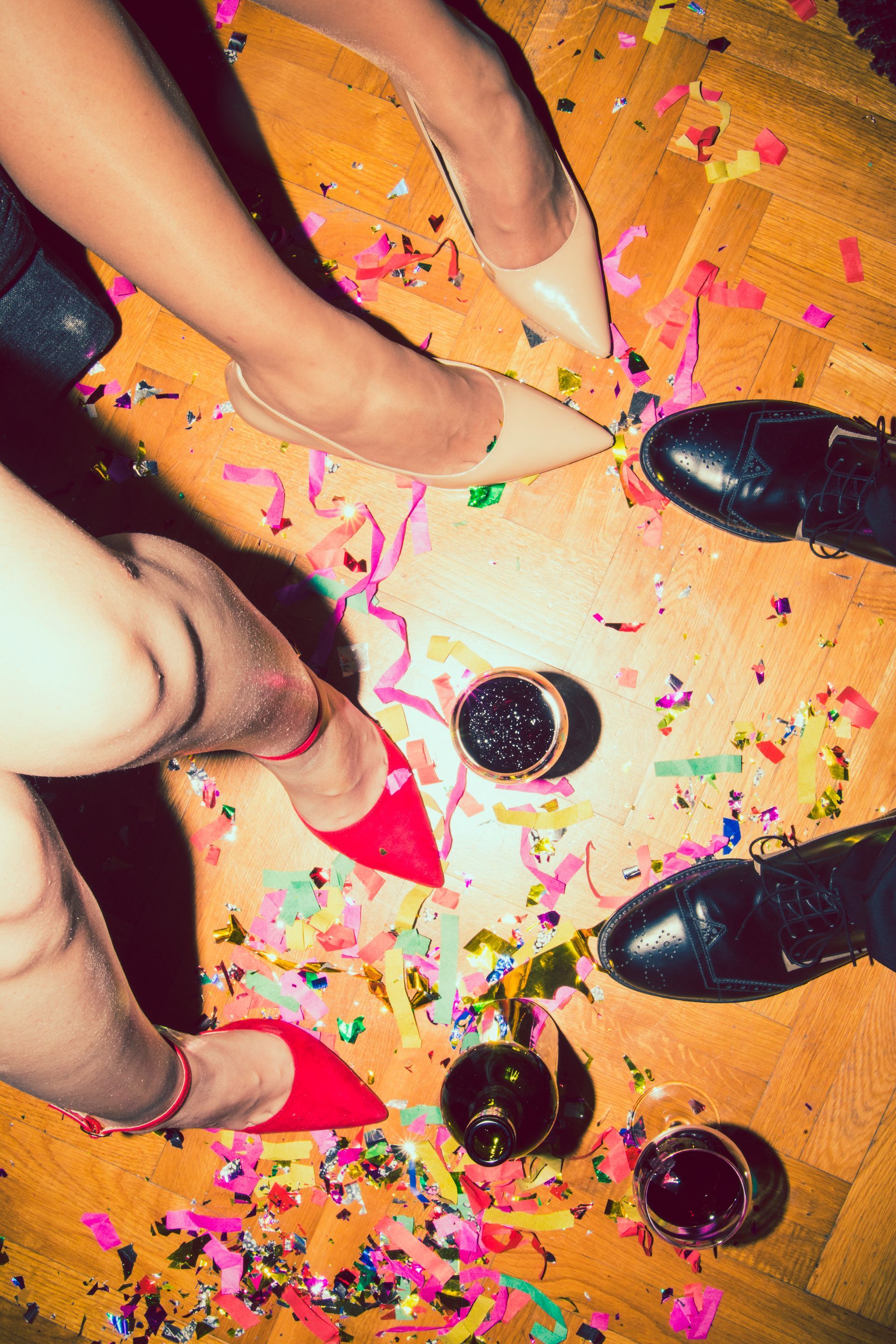A group of people standing on a wooden floor with confetti and bottles.