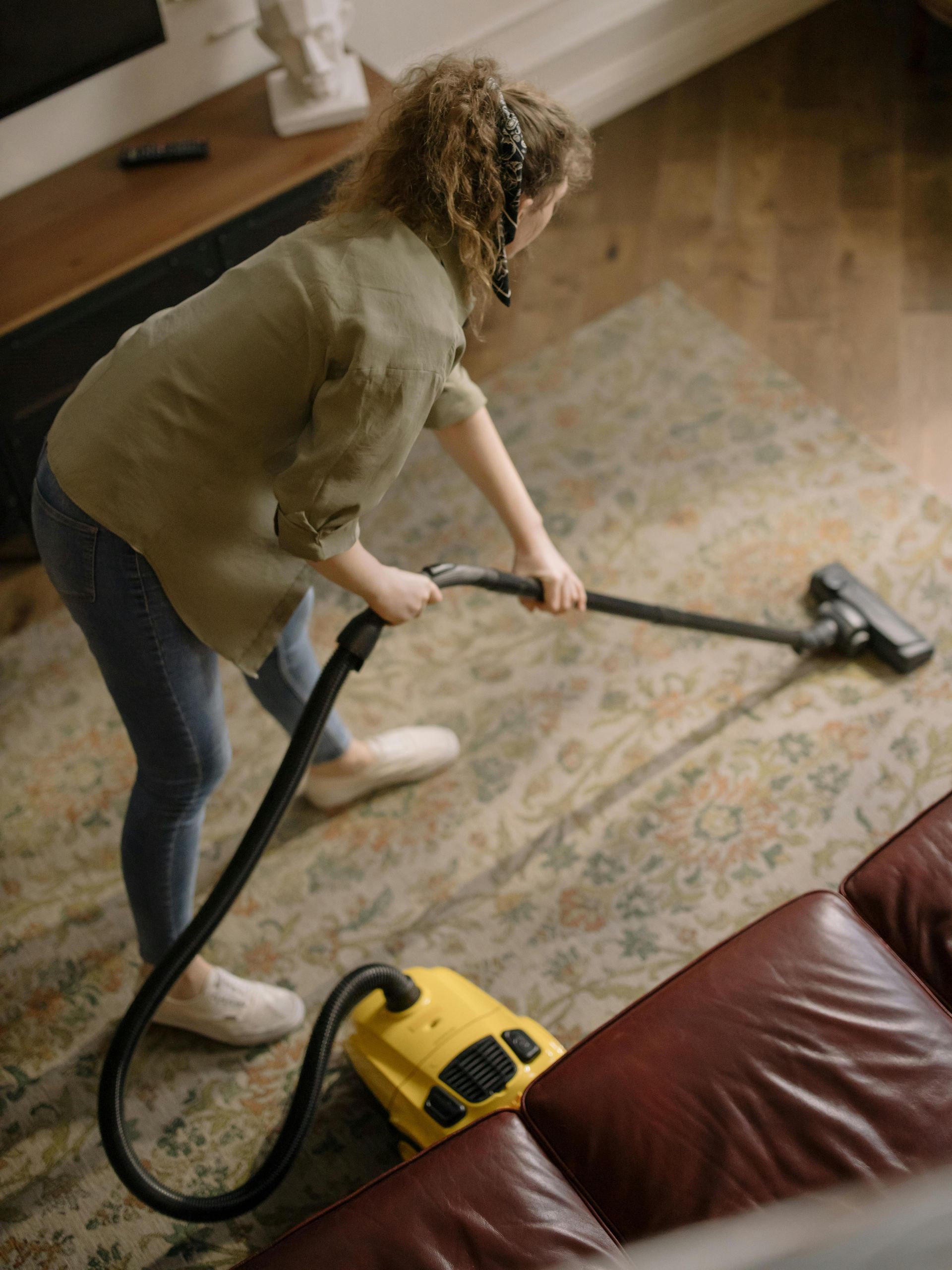 A woman is vacuuming the floor in a living room.