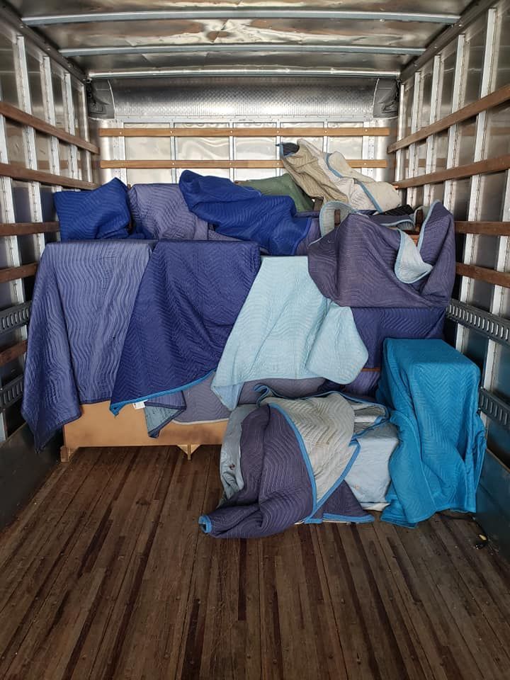 The inside of a moving truck filled with furniture and blankets.