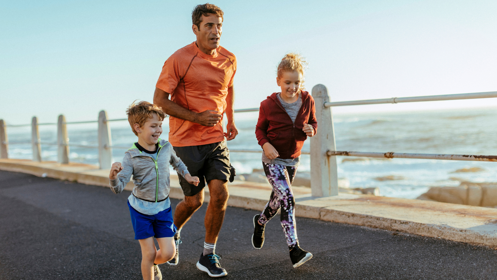 Two kids running with an adult