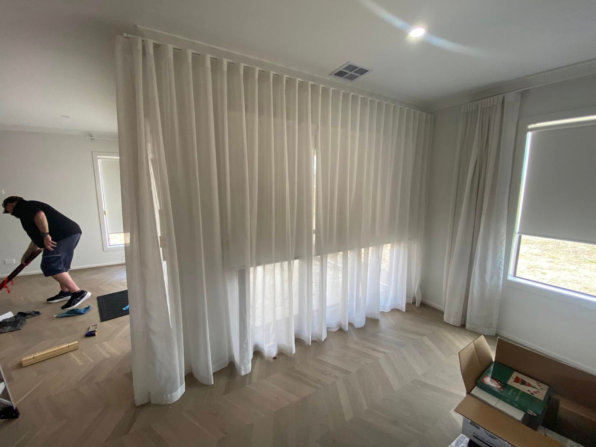 A Man Is Standing In A Room With White Curtains And Blinds  — Night & Day Blinds and Awnings in Pakenham, VIC
