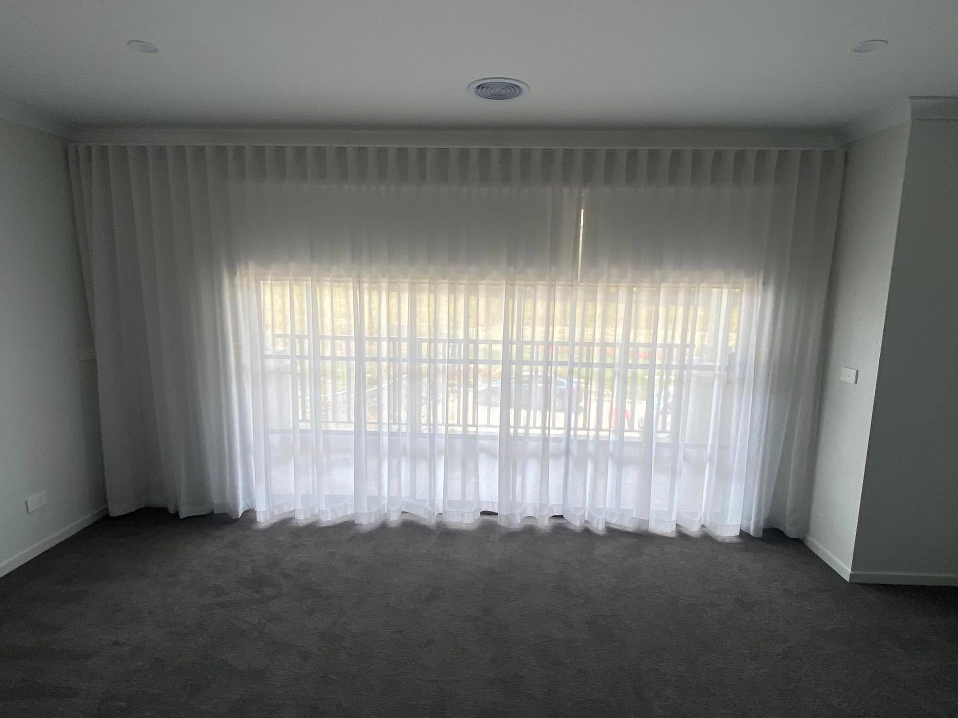 A Living Room With A Large Window And White Curtains  — Night & Day Blinds and Awnings in Pakenham, VIC