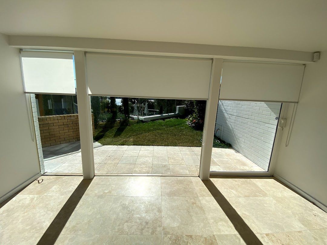 White Roller Blinds Are Covering A Window In A Room  — Night & Day Blinds and Awnings in Pakenham, VIC