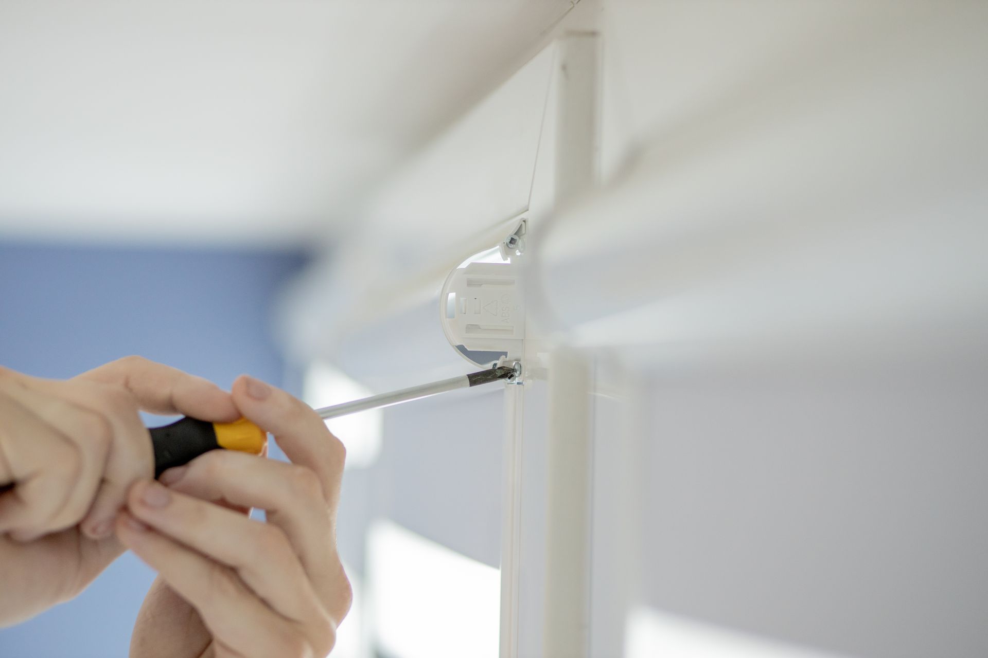 A professional repairing a roller blinds cassette header on a window 