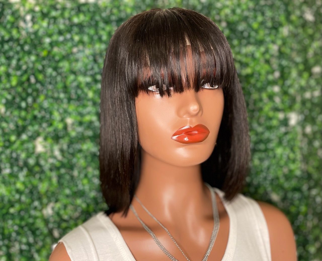 A mannequin wearing a wig with bangs and red lips.