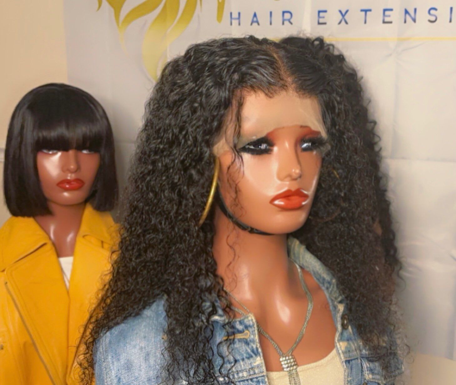 A mannequin with curly hair is standing next to a mannequin with short hair.