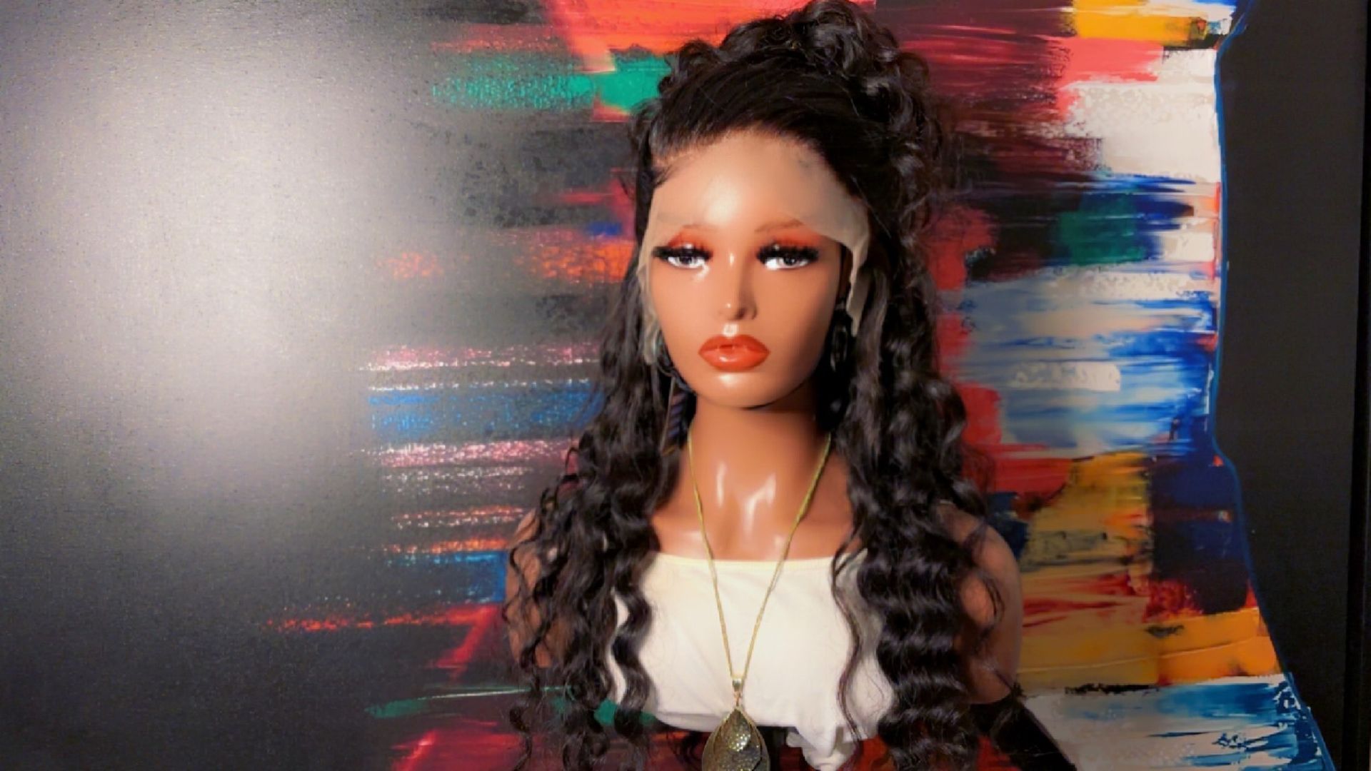 A mannequin wearing a wig is standing in front of a painting.