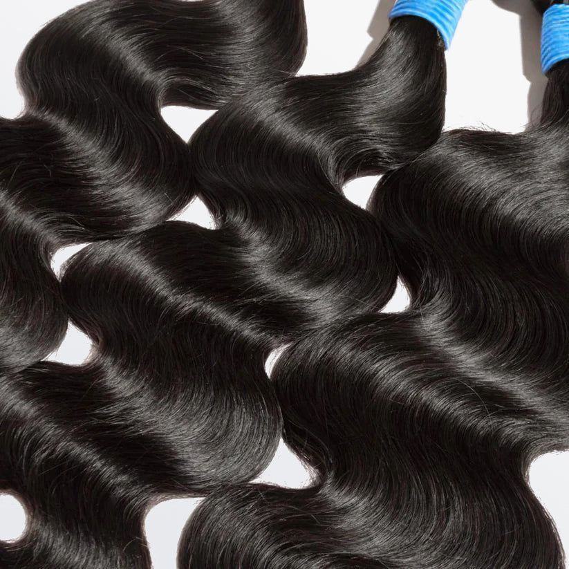A close up of two bundles of black hair on a white surface.