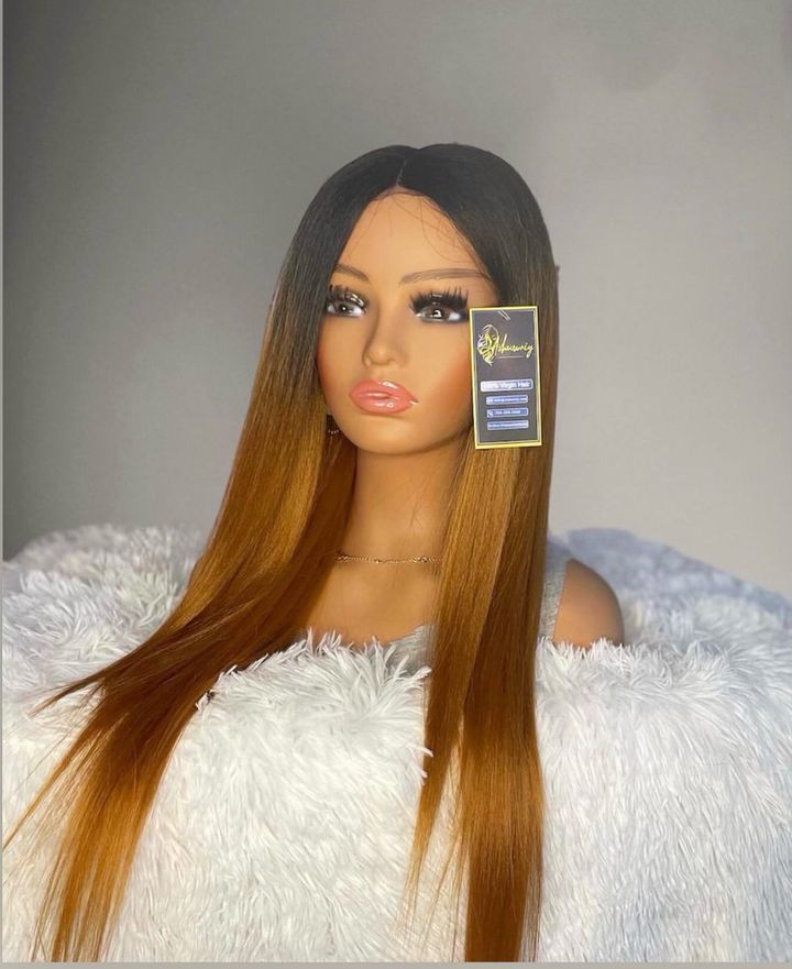 A mannequin wearing a wig is sitting on a white blanket.