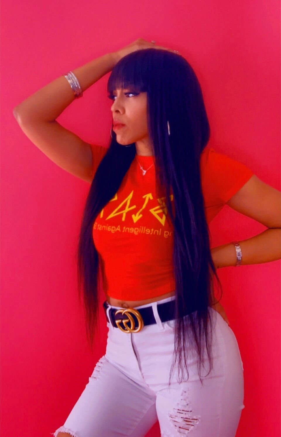 A woman with long black hair is wearing a red t-shirt and white jeans