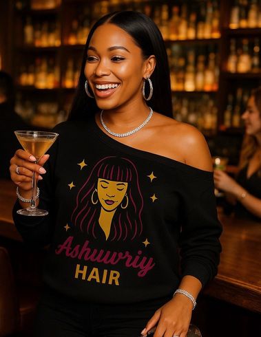 Woman in black sweater with graphic, holding a drink, smiling at bar.