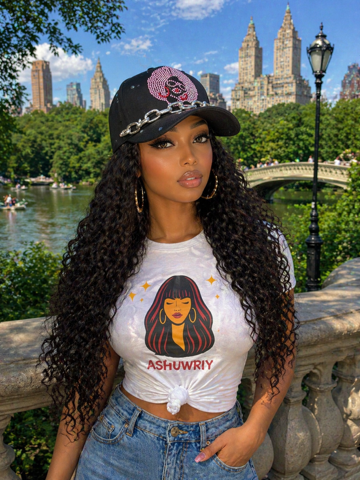 Woman in a black cap and white graphic tee posing by a park bridge with a city skyline behind her