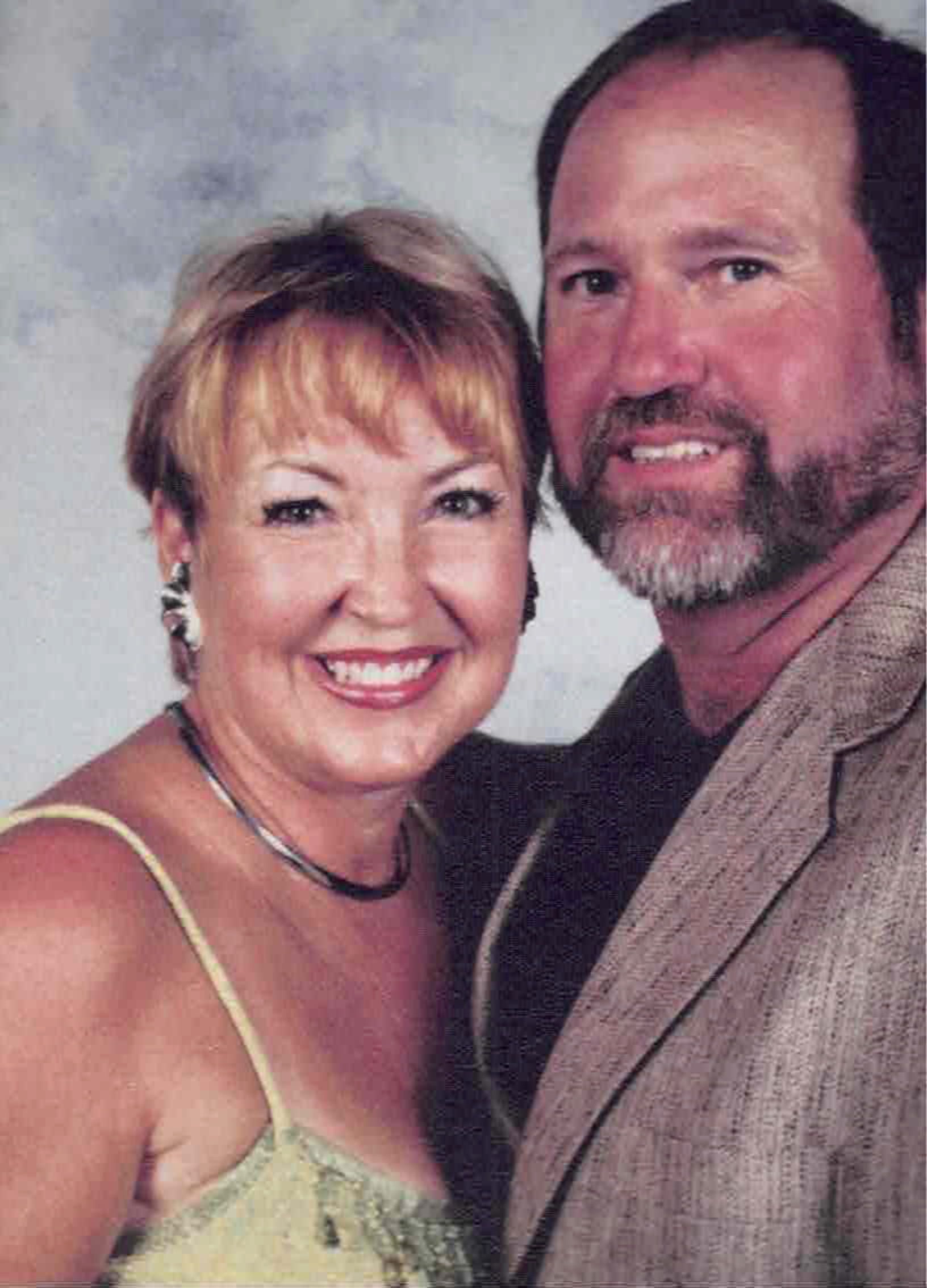 A man and a woman are posing for a picture and smiling for the camera.
