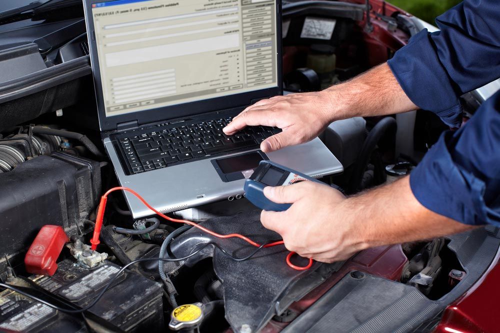 A Man Is Using A Laptop Computer Under The Hood Of A Car — Edmonton Car Air in Smithfield, QLD