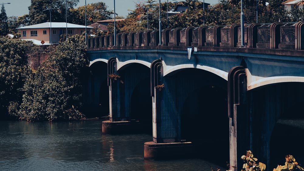A Bridge Over A Body Of Water With A House In The Background — Edmonton Car Air in Innisfail, QLD
