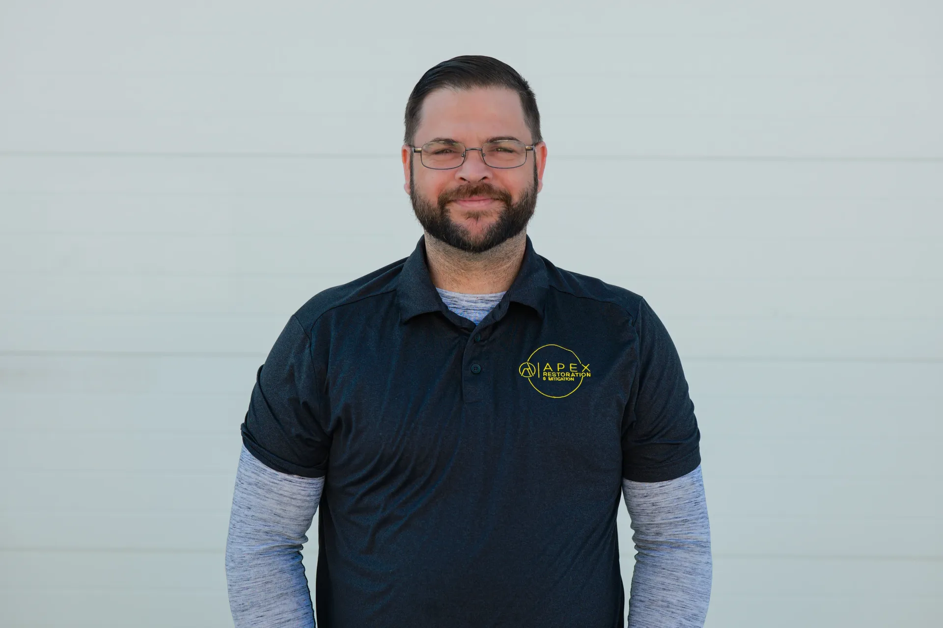 Woman with dark curly hair smiles, eyes closed, hand in hair, wearing polka dot top.