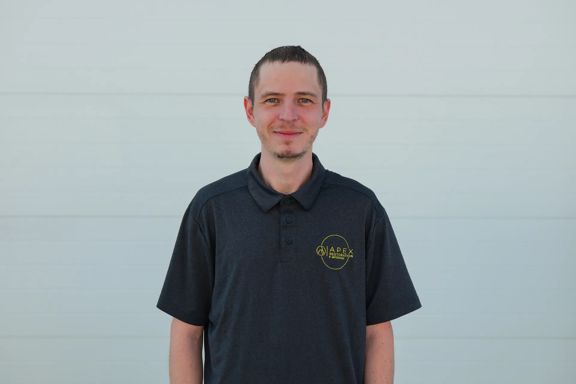 Woman with dark curly hair smiles, eyes closed, hand in hair, wearing polka dot top.