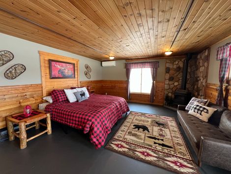 A bedroom with a bed , couch , rug and fireplace.