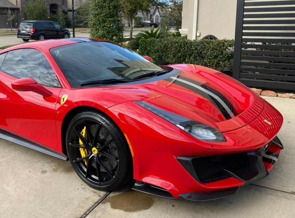A red ferrari 488 pista is parked in a driveway. A red ferrari 488 pista is parked in a driveway.