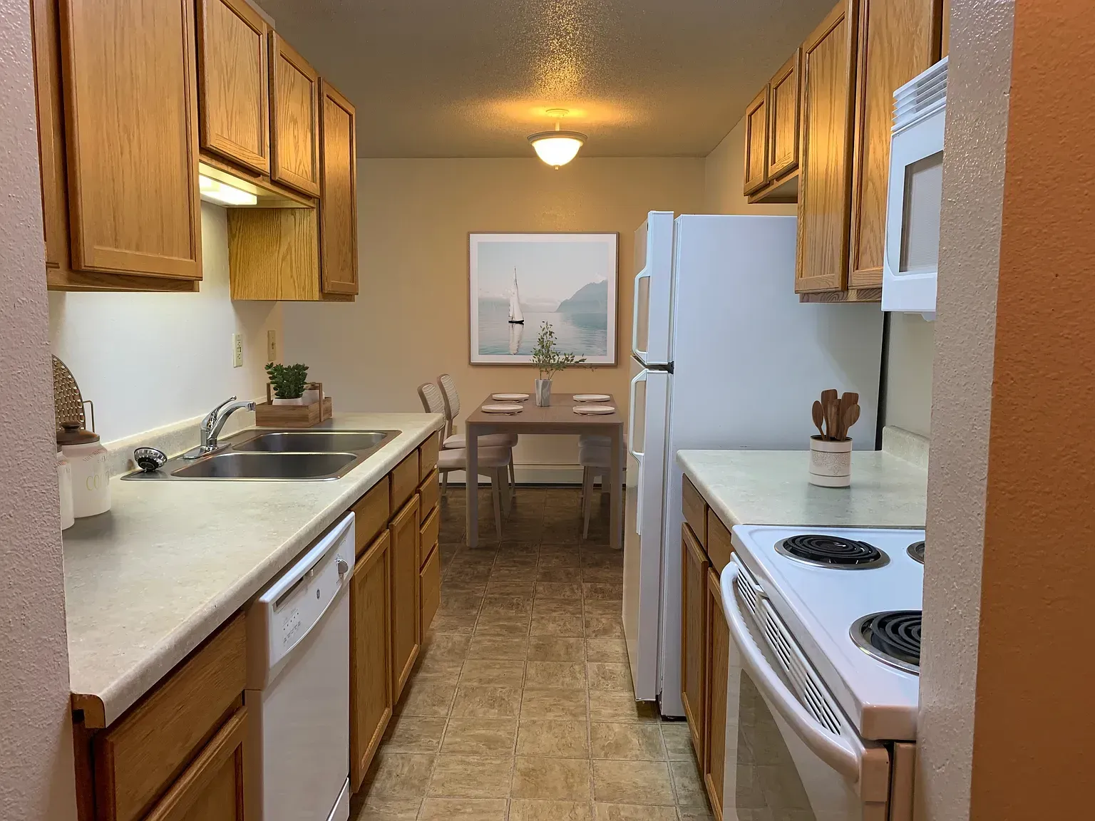 Kitchen with wooden cabinets, white appliances, and a dining table in the background.