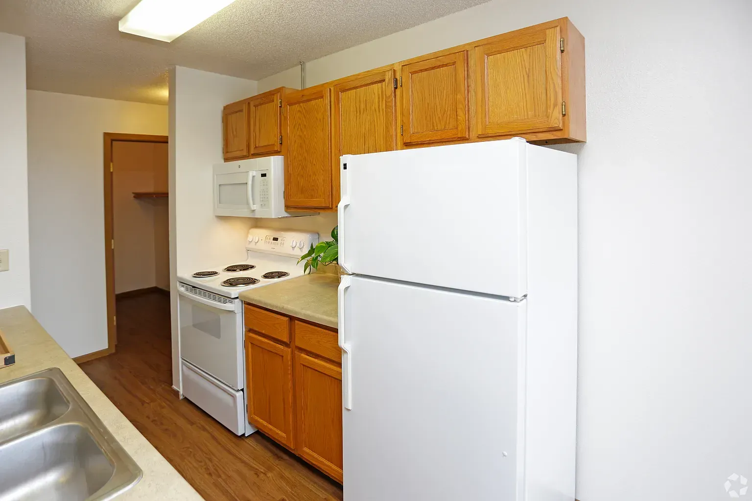 Kitchen with wood cabinets, white appliances, and a hallway entrance.