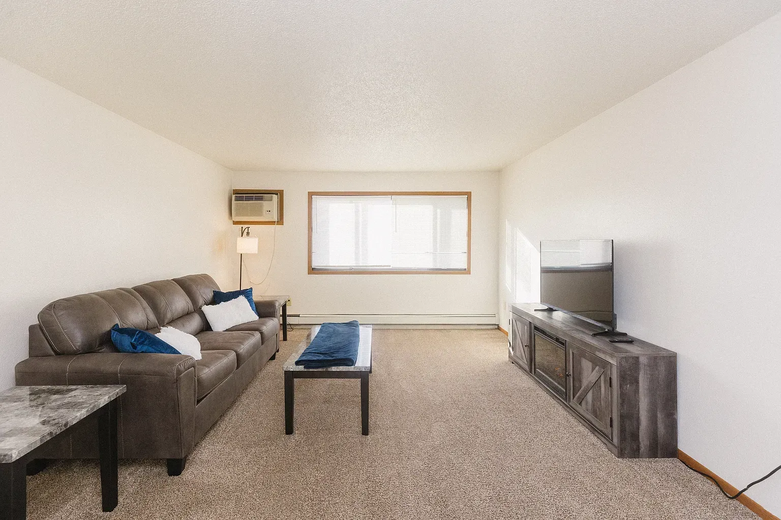 Brown leather couch in living room with TV, rug, and coffee table.