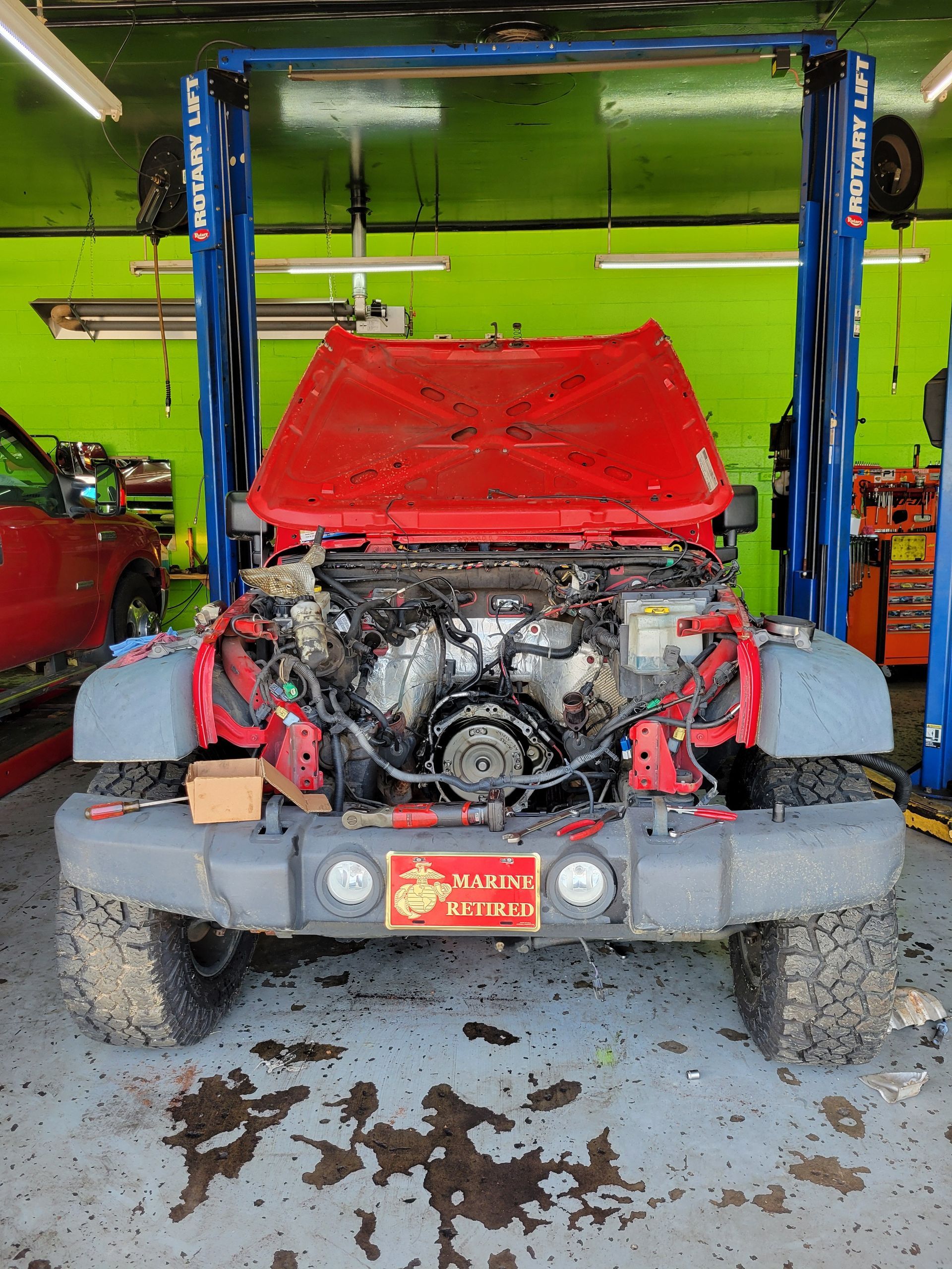 Red Jeep with hood open on a hydraulic lift