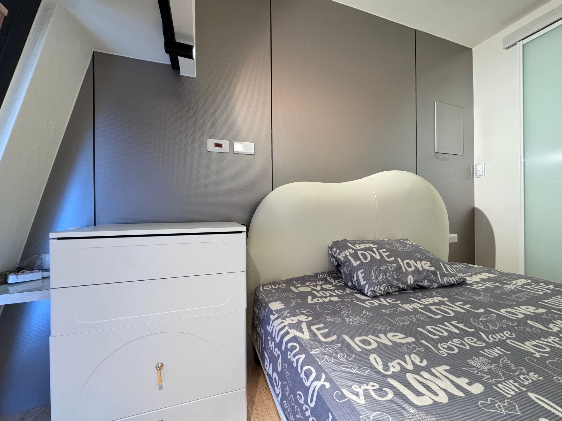 A bedroom with a bed and a dresser with the word love on it