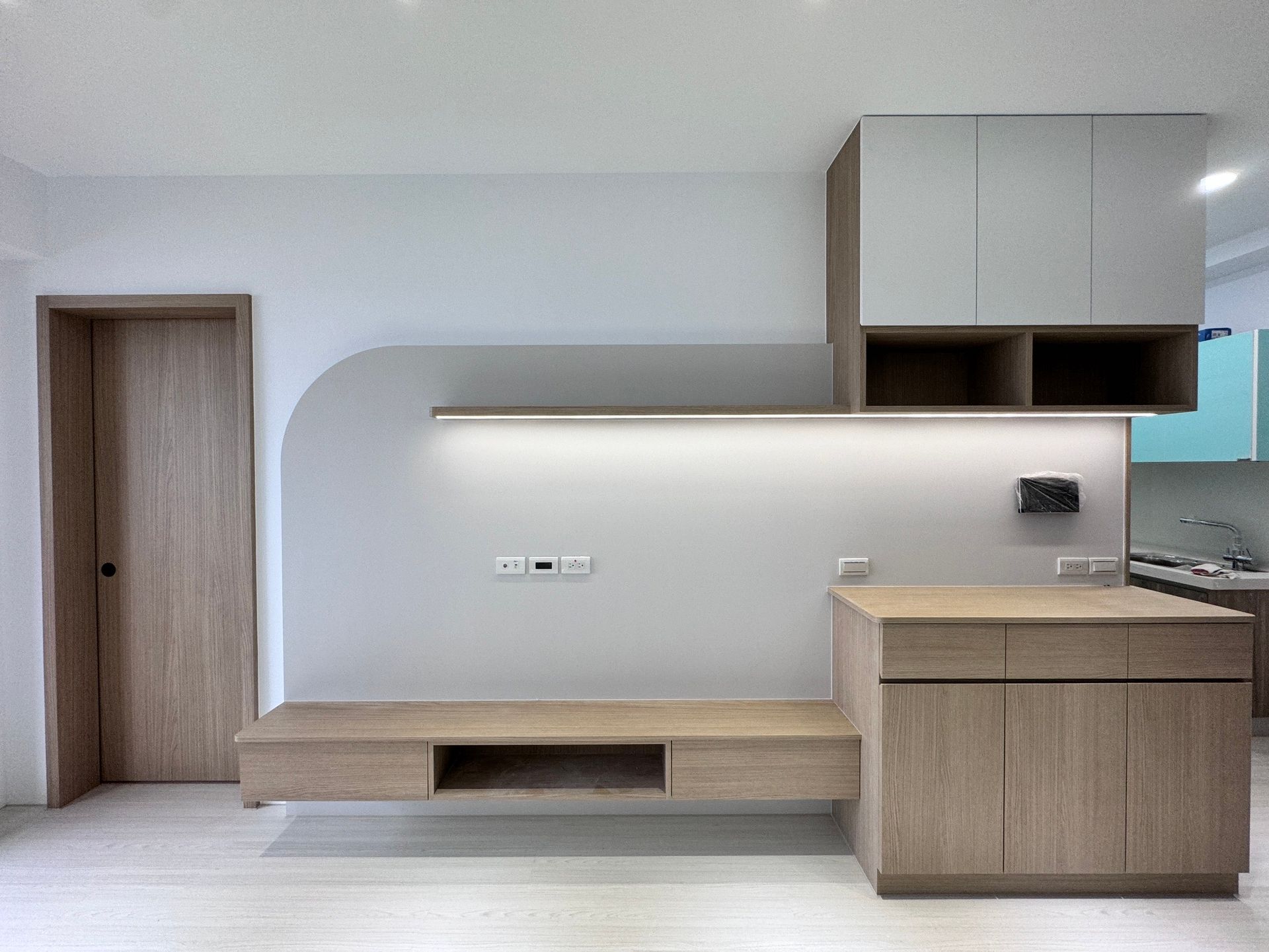A living room with a television mounted to the wall and a wooden entertainment center.