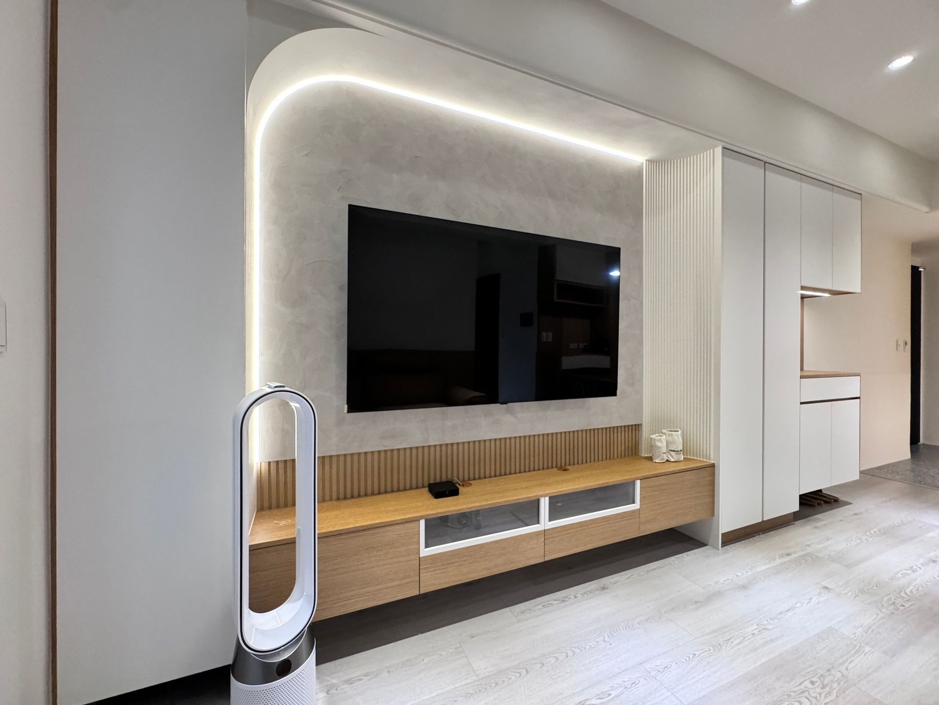 A living room with a flat screen tv and a fan.