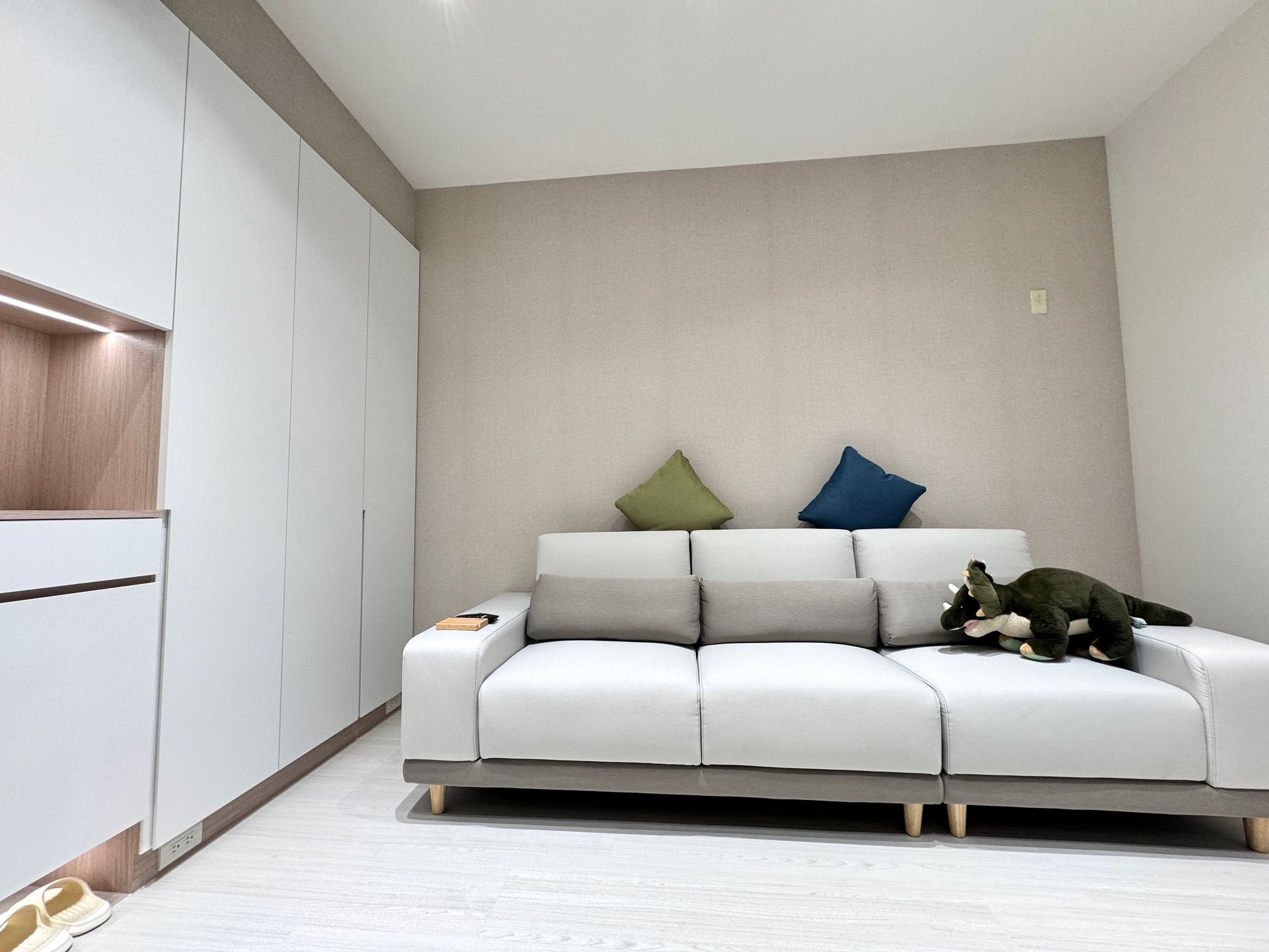 A living room with a white couch and a stuffed animal on it.