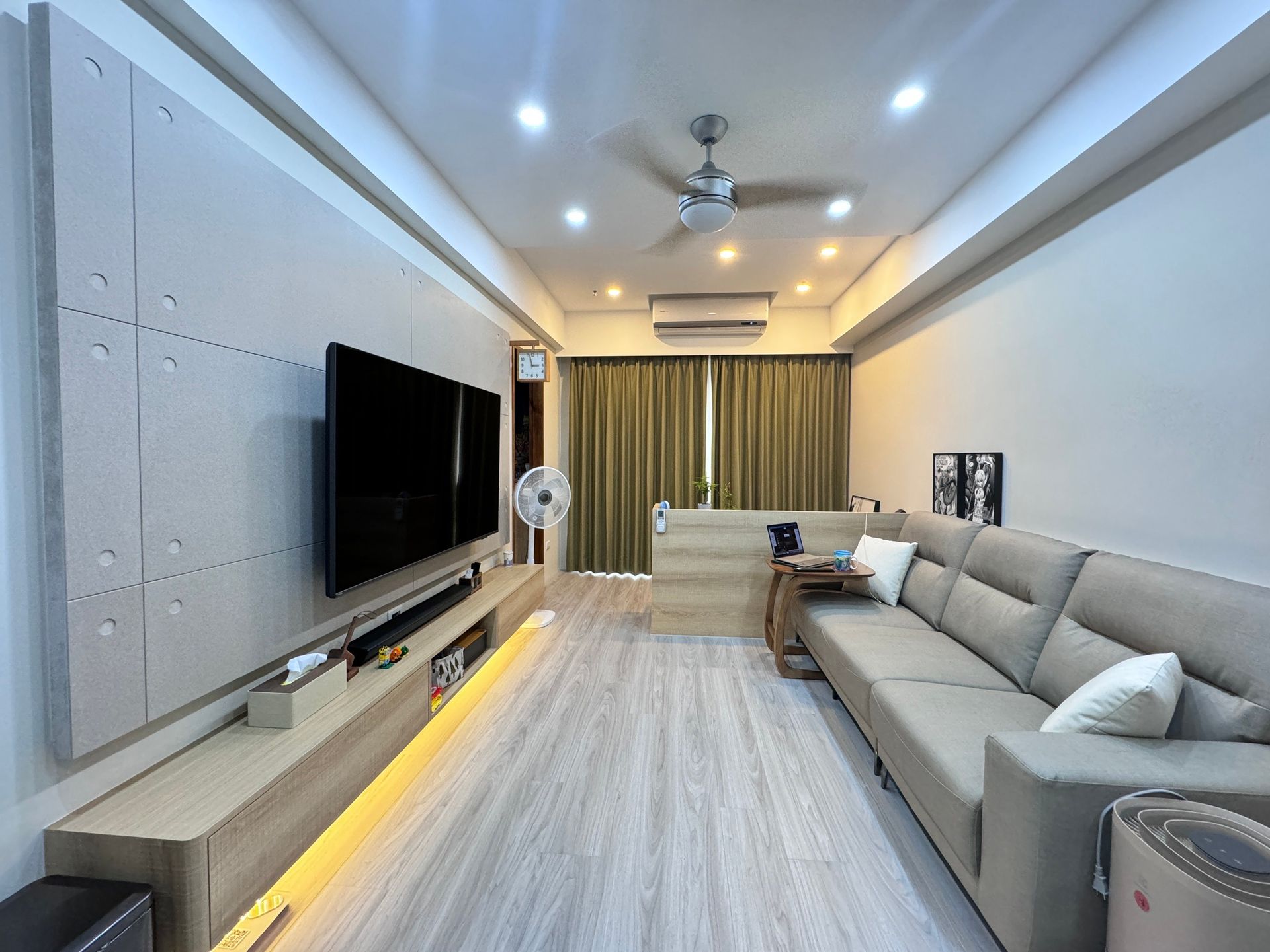 A living room with a couch , television , and ceiling fan.