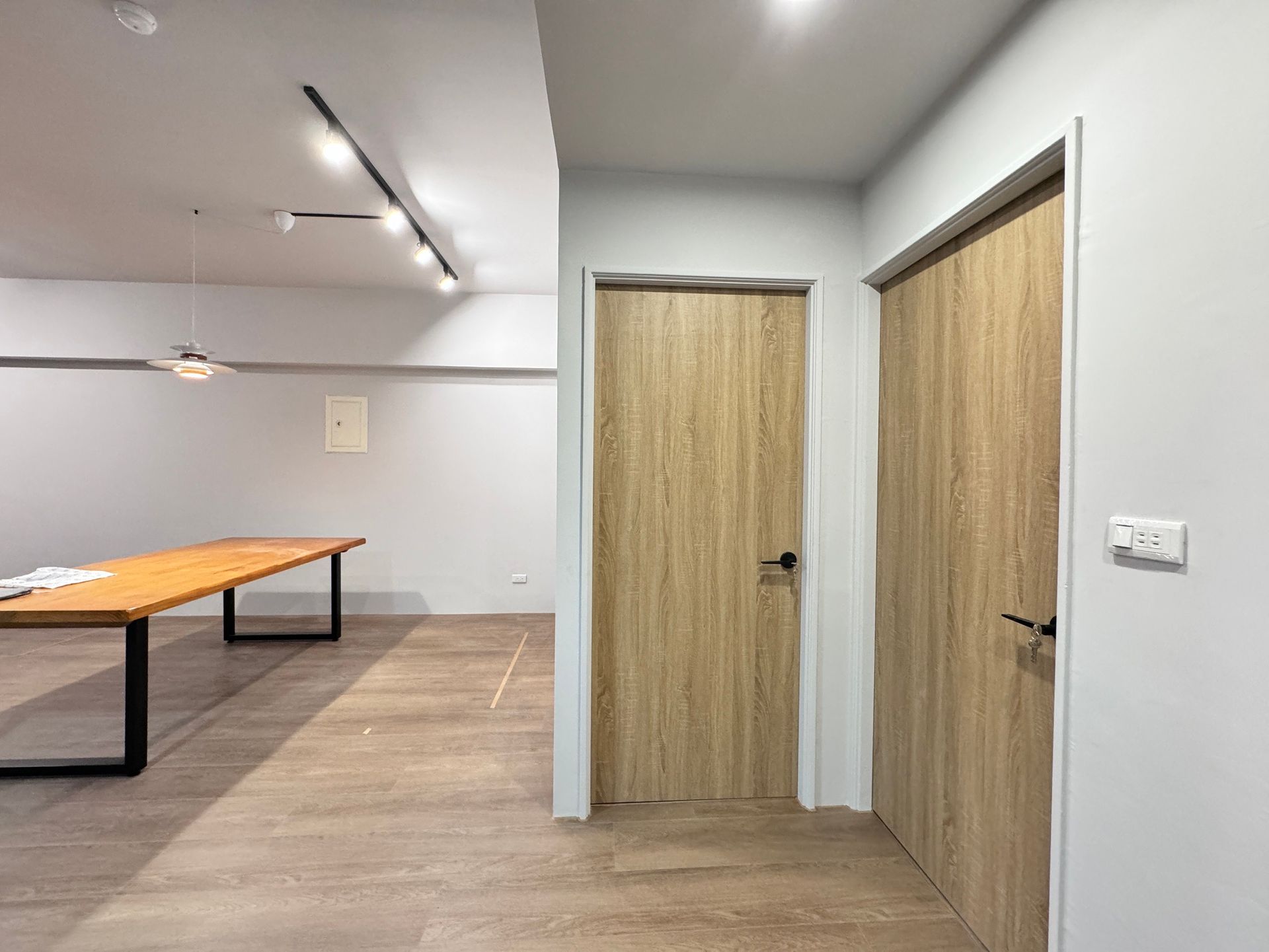 A hallway with two wooden doors and a wooden table.