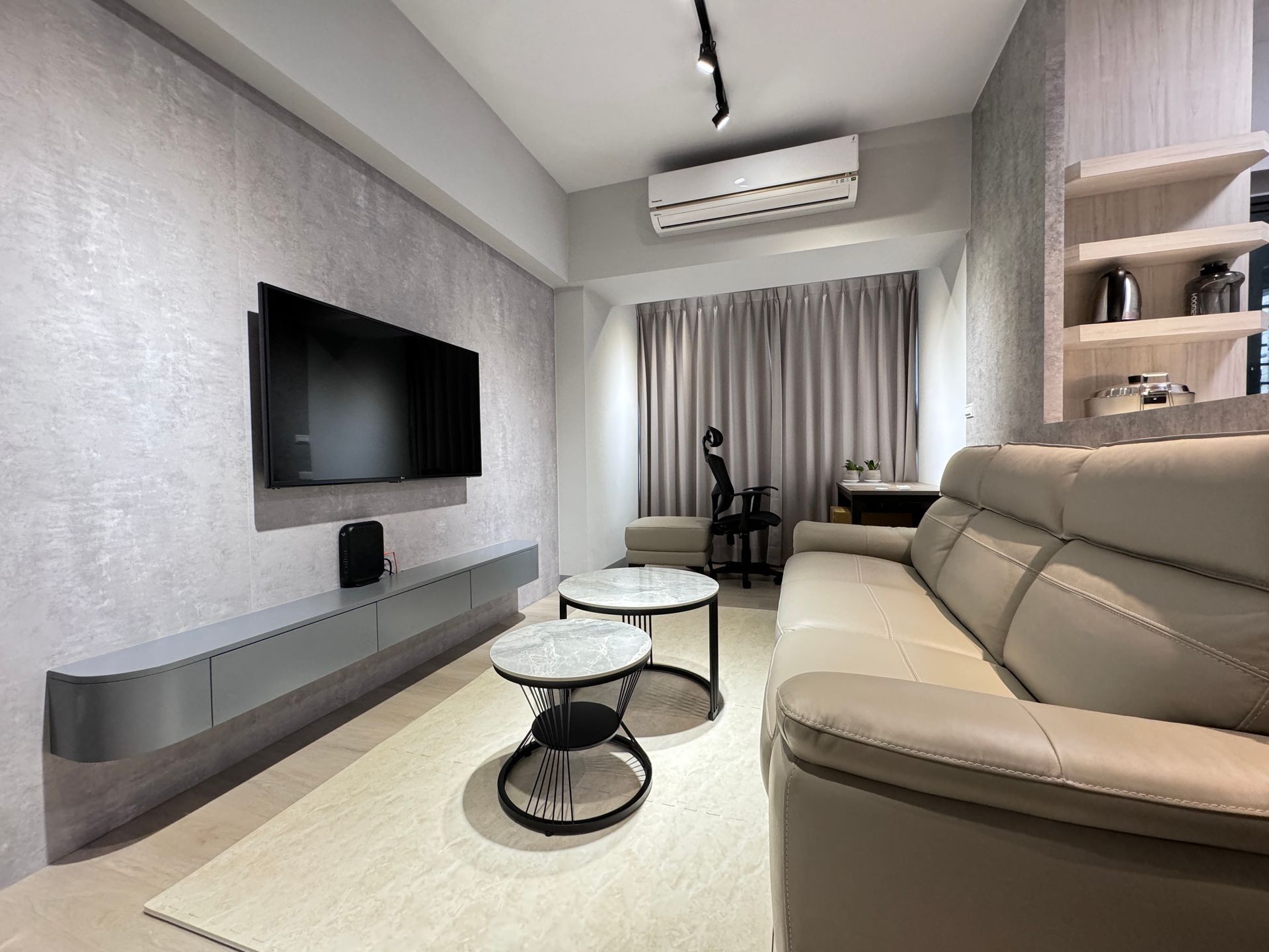 A living room with a couch , two coffee tables , a flat screen tv and a desk.