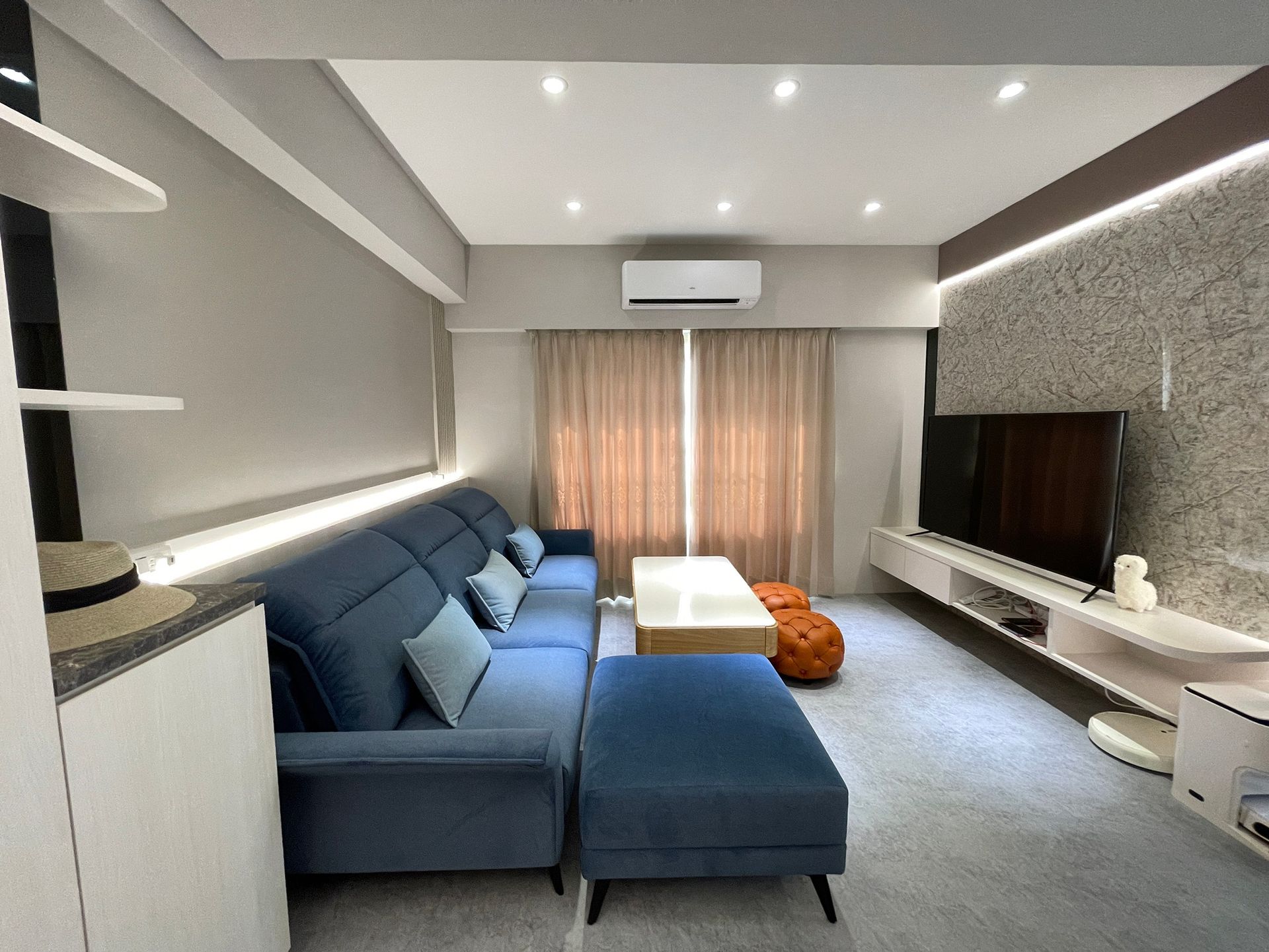 A living room with a blue couch and a flat screen tv.