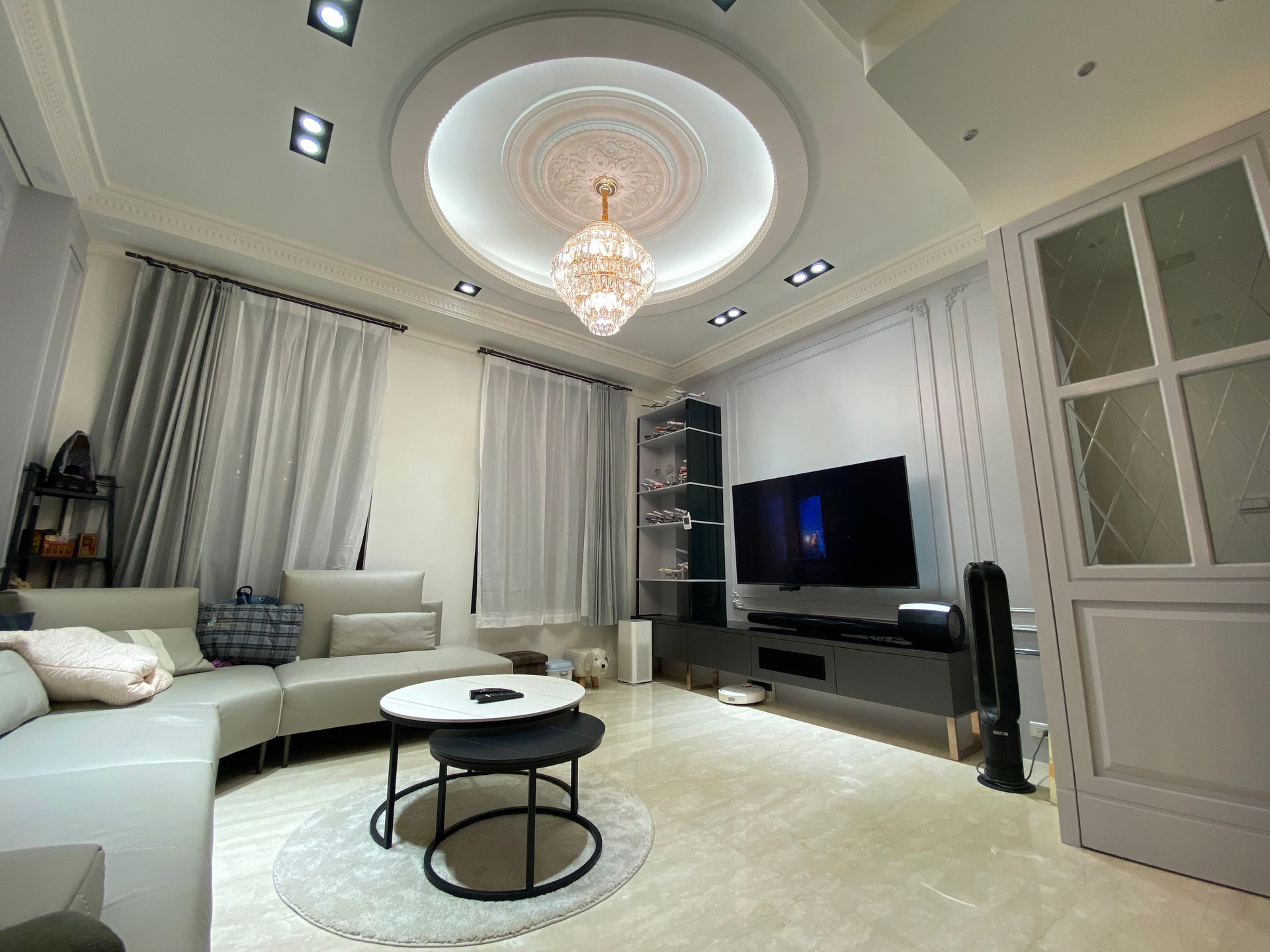 A living room with a couch , table , television and chandelier.
