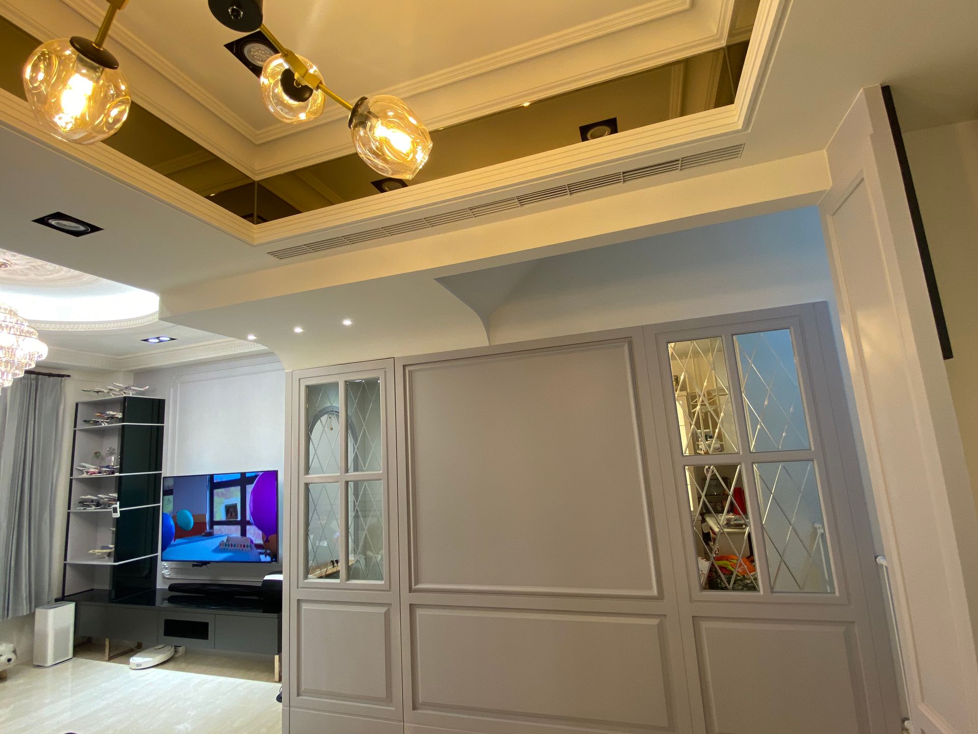 A living room with a flat screen tv and a mirrored ceiling.