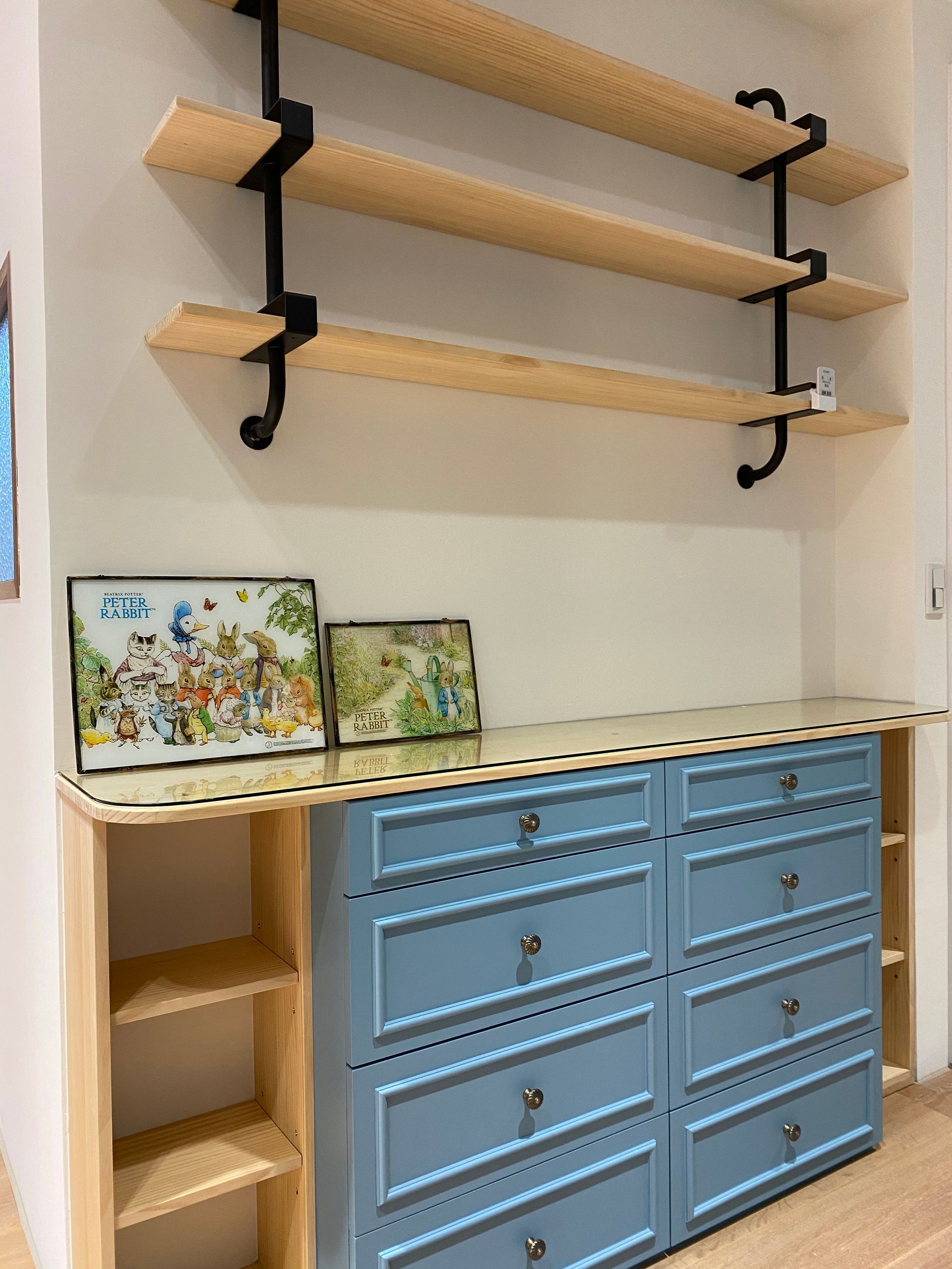 A blue dresser with wooden shelves above it in a room.