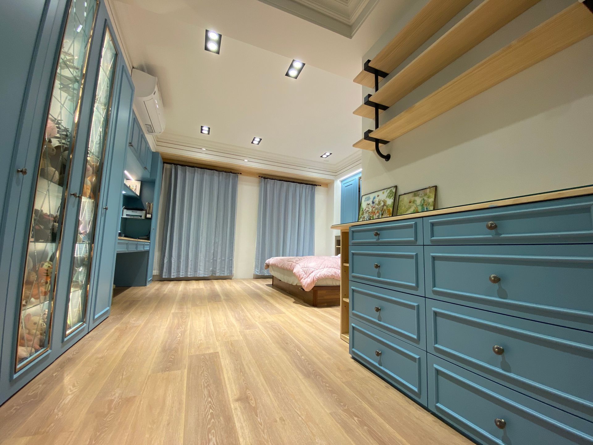 A bedroom with a bed , dressers and shelves.