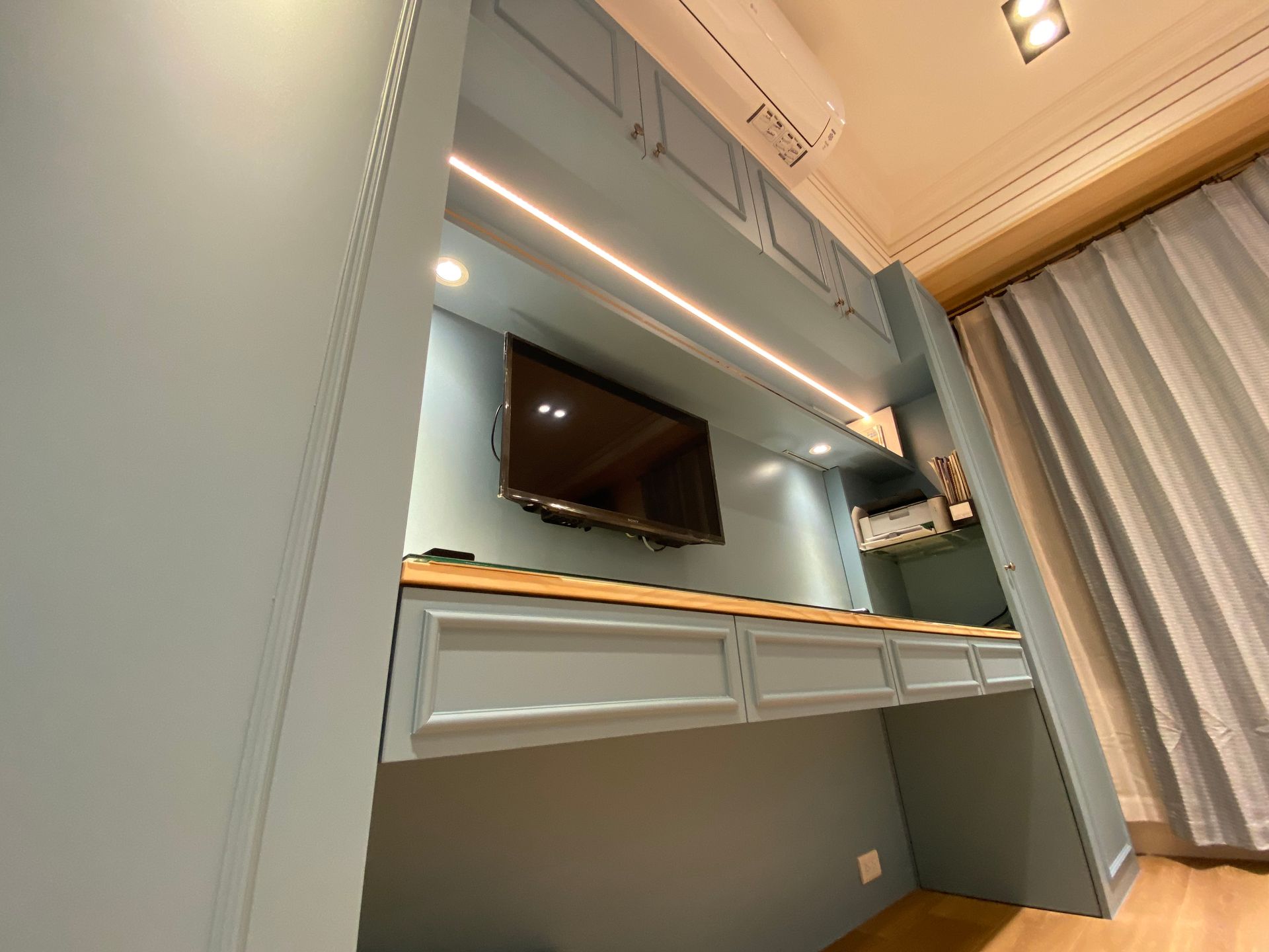 A room with a desk and a television on the wall.