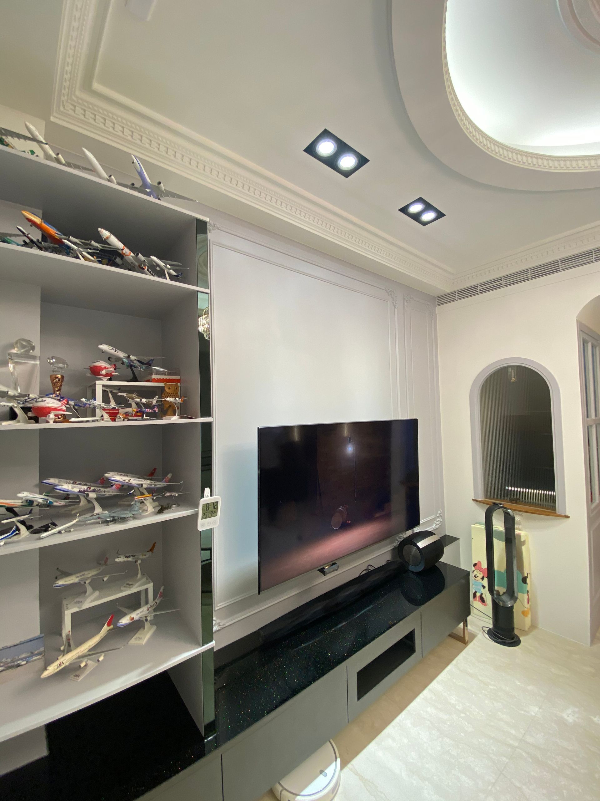 A living room with a flat screen tv and shelves filled with lego planes.