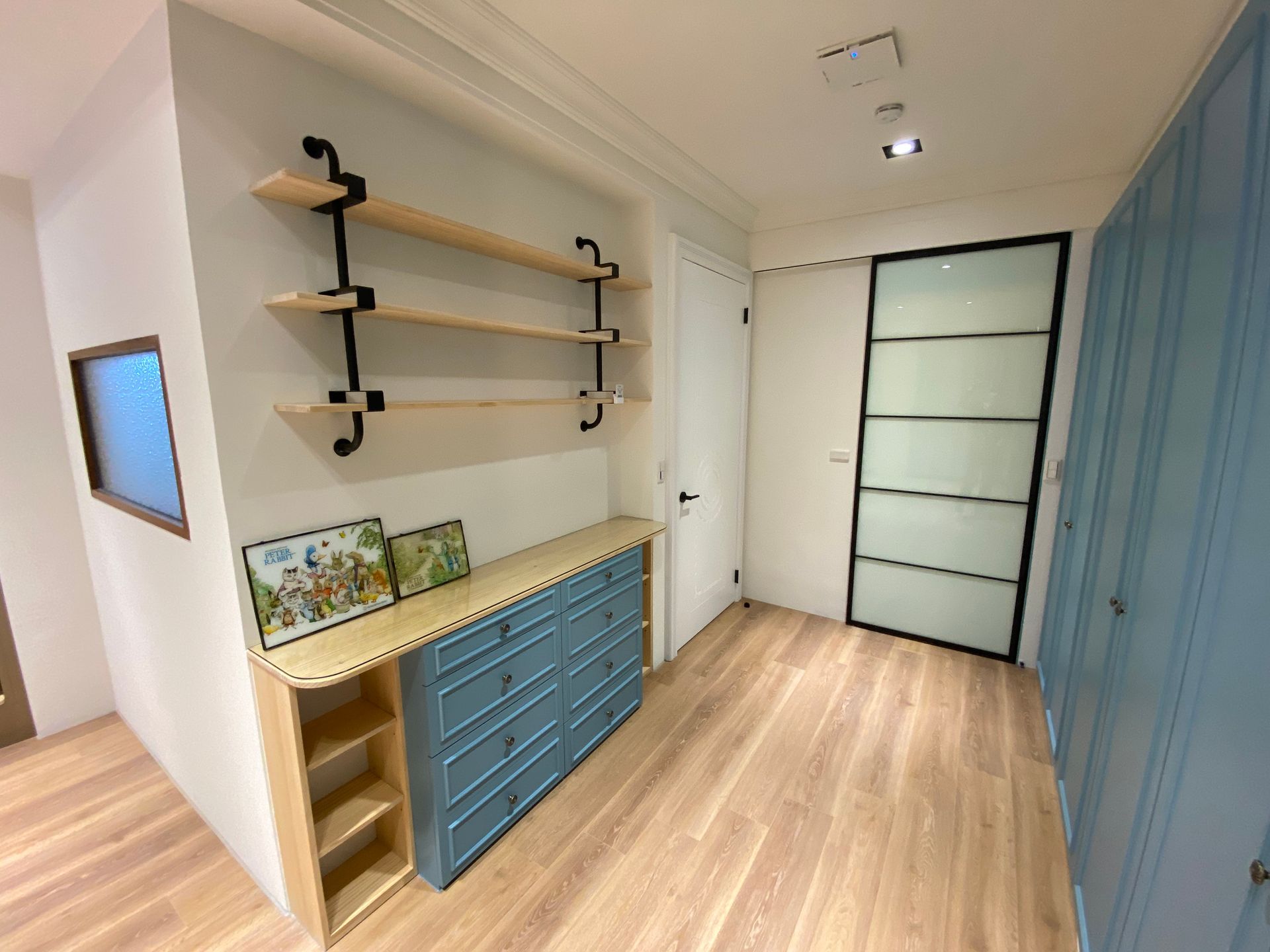 A hallway with a dresser , shelves , and a door.