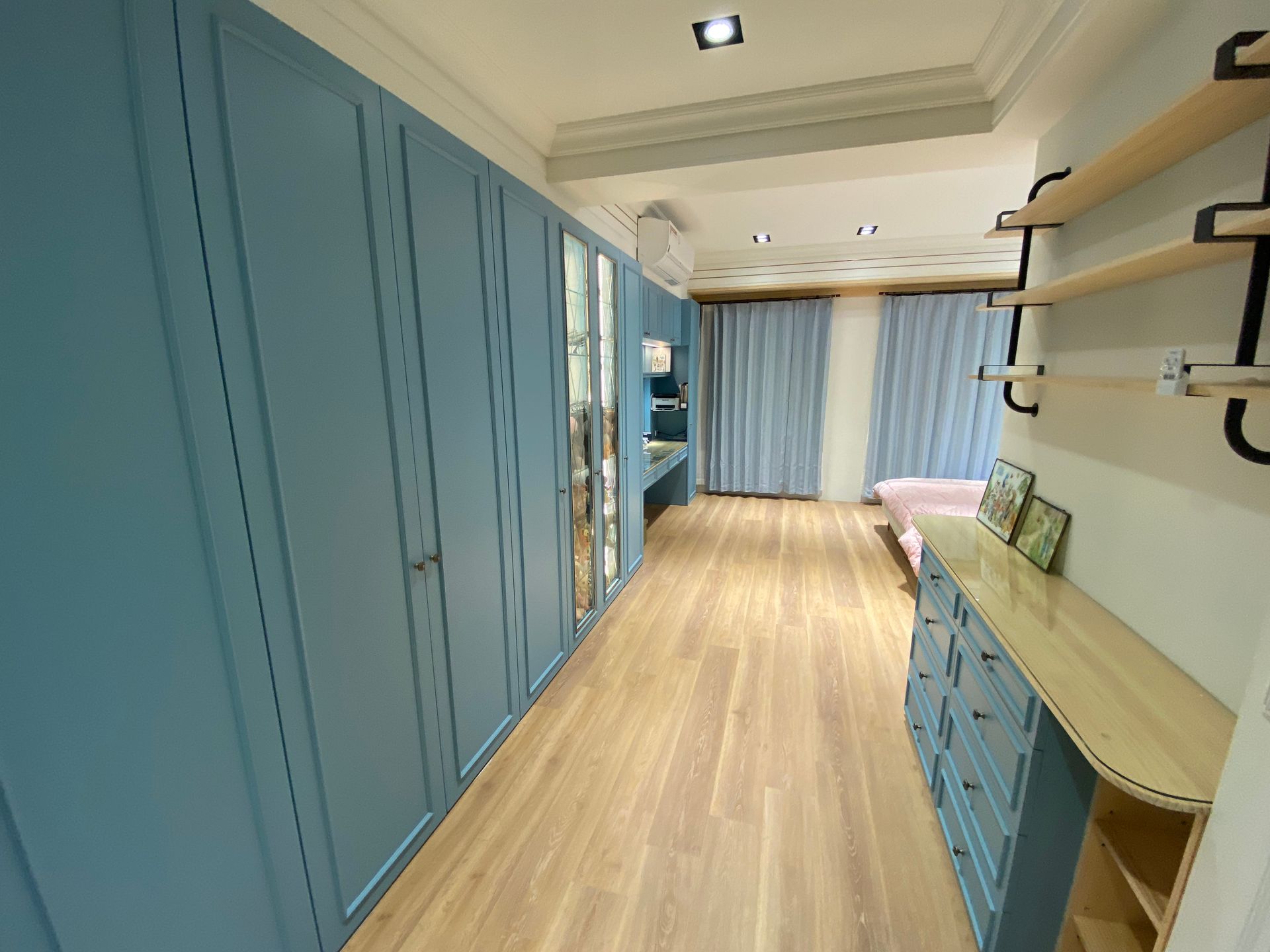 A long hallway with blue cabinets and wooden floors