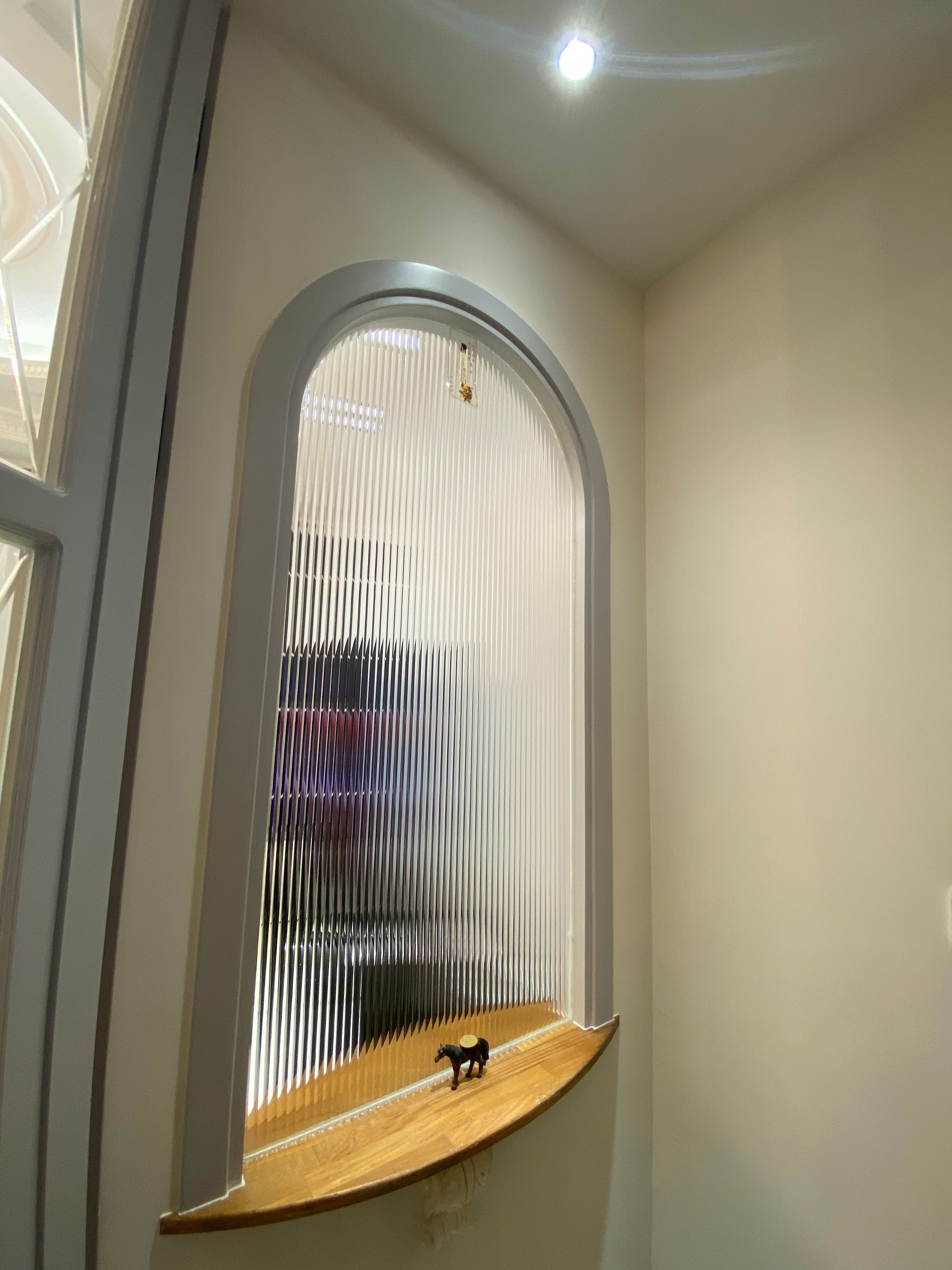 A window with a wooden shelf in the corner of a room.
