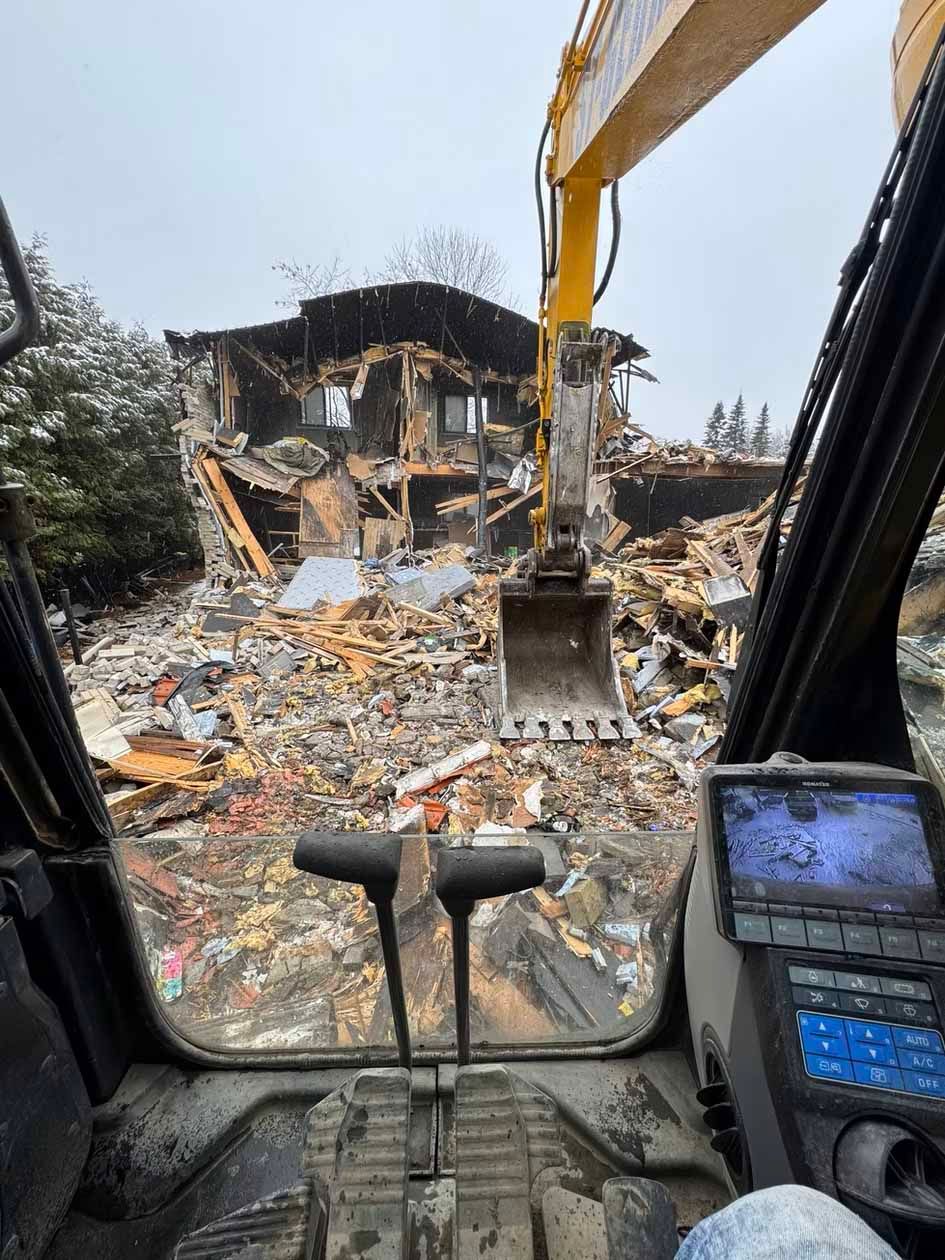 Une vue d'une maison en cours de démolition depuis l'intérieur d'une excavatrice.