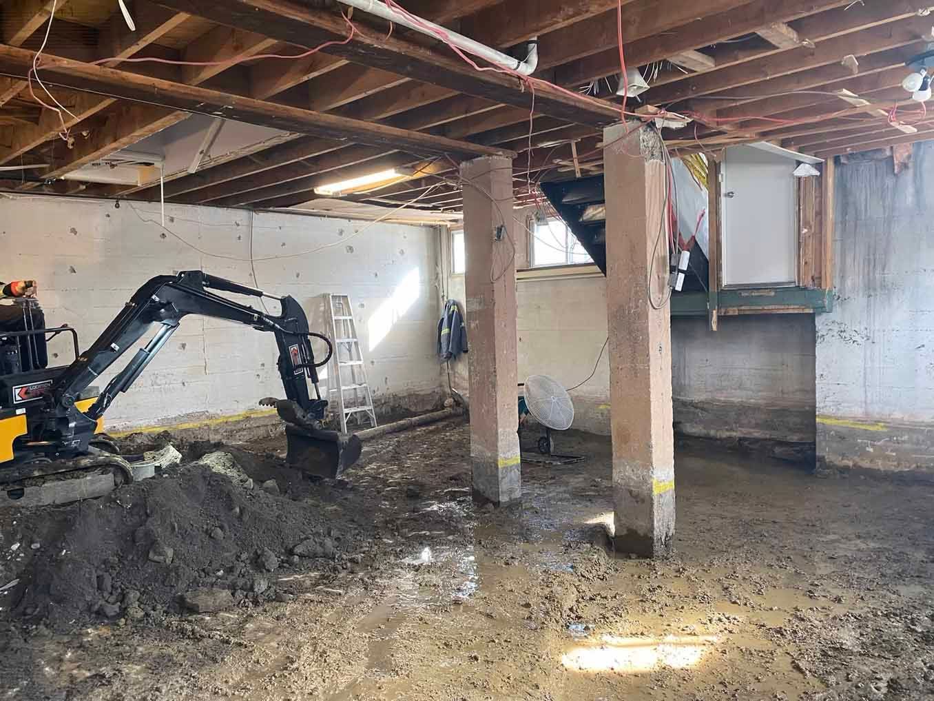 Une petite excavatrice creuse un trou dans un sous-sol.