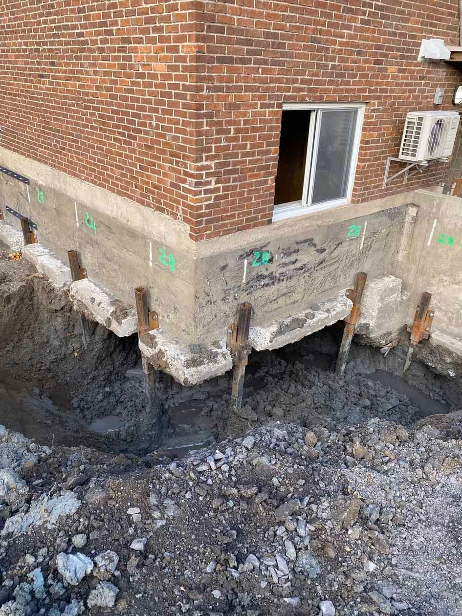 Un bâtiment en briques avec un trou dans le sol devant lui.